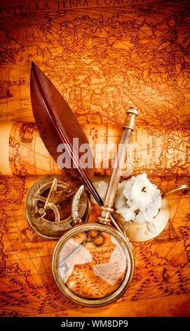 Vintage Kompass, Lupe, Taschenuhr, Federkiel, Spyglass liegen auf einer alten antiken Karte 1565 mit eine brennende Kerze. Vintage Stillleben. Stockfoto