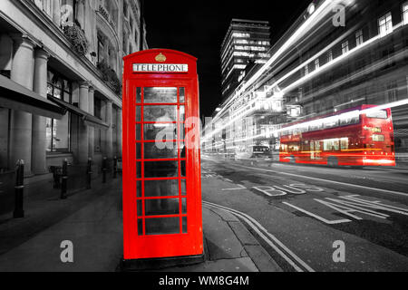 Iconic Red Telefon, klassische britische Entwurf, Stand über sich schnell bewegenden Verkehr mit leichten Wanderwegen. Stockfoto