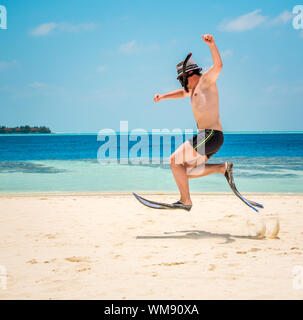 Lustiger Mann springt in Flossen und Maske. Urlaub an einem tropischen Strand auf den Malediven Inseln. Stockfoto
