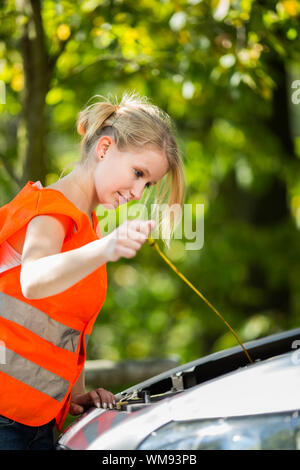 Junge Fahrerin am Straßenrand eine Warnweste tragen, nachdem ihr Auto ist kaputt Stockfoto