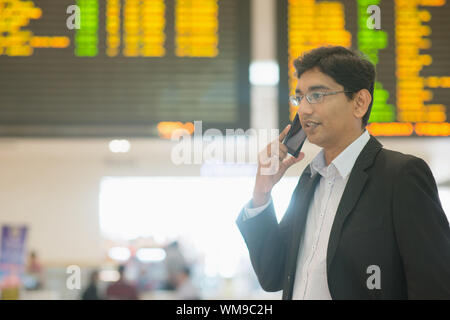 Asiatischen indischen Geschäftsmann am Telefon während seiner Geschäftsreisen, am Flughafen. Stockfoto