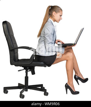 Geschäftsfrau, sitzen auf den Rand der Bürostuhl, mit Laptop auf den Knien. auf den Bildschirm schauen. Auf weissem Hintergrund Stockfoto