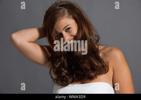 attraktive junge Frau mit lange gewellte dunkles Haar Frisur Beauty Portrait lächelnd Stockfoto