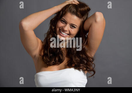 attraktive junge Frau mit lange gewellte dunkles Haar Frisur Beauty Portrait lächelnd Stockfoto