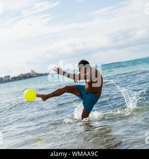 Glückliche junge erwachsene Mann spielen Beach Ball im Sommer Stockfoto