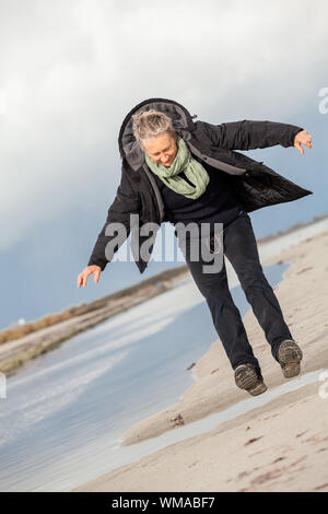 Gerne ältere Frau Herumtollen am Strand Stockfoto