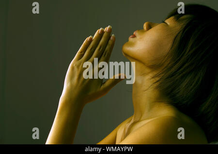 Frau mit Händen in Low Key gefaltet Stockfoto