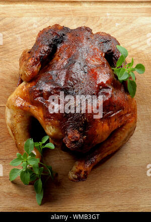 Ganzen gebratene Hähnchen mit frischem Basilikum Blätter closeup auf Holz Schneidebrett Stockfoto