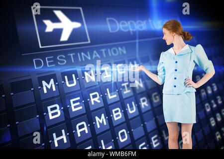 Hübsche Stewardess, die mit einer Hand gegen Blue Departures Board für deutsche Städte Stockfoto