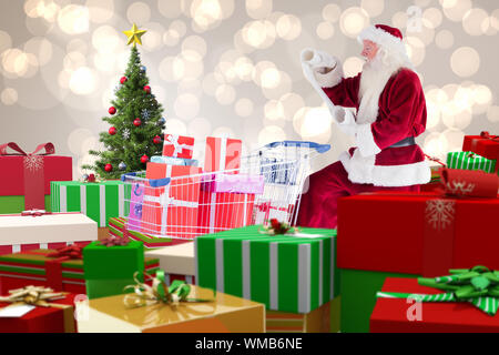 Santa mit Geschenken von Karre gegen Weihnachtsbaum Stockfoto