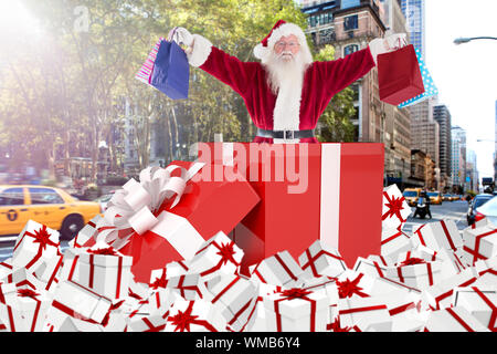 Das zusammengesetzte Bild von Santa steht in großen Geschenk gegen new york street Stockfoto