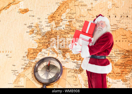 Santa trägt ein paar Geschenke gegen Weltkarte mit Kompass, Europa und im Nahen Osten Stockfoto