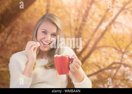 Hübsche Blondine genießen Sie heiße Schokolade auf der Couch gegen ruhigen Herbst Szene im Wald Stockfoto