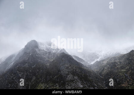 Atemberaubende Moody dramatische Winterlandschaft mountain Bild von schneebedeckten Y Garn in Snowdonia Stockfoto