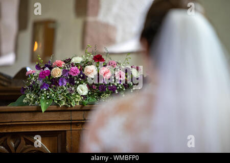 Braut sass in der Kirche mit Blumen im Hintergrund Stockfoto