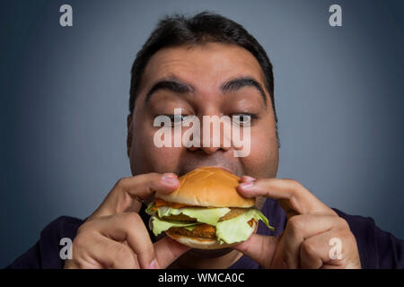 Nahaufnahme von Fat man Essen burger halten Sie es mit beiden Händen Stockfoto