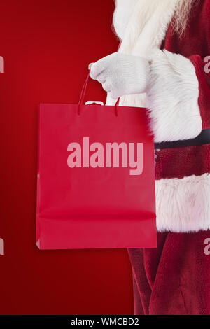 Santa trägt rot Geschenkbeutel gegen roter Hintergrund Stockfoto