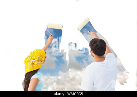 Das zusammengesetzte Bild der glücklichen jungen Paar malen gemeinsam ein Himmel auf der weißen Wand Stockfoto