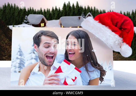 Frau überraschend Freund mit Geschenk gegen niedlichen Dorf im Schnee Stockfoto
