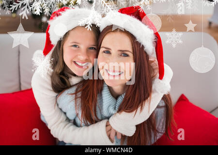 Festliche Mutter und Tochter auf der Couch gegen hängende Dekorationen Stockfoto