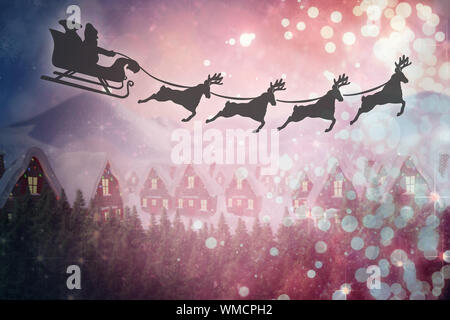 Silhouette der Weihnachtsmann und Rentier gegen niedlichen Dorf im Schnee Stockfoto