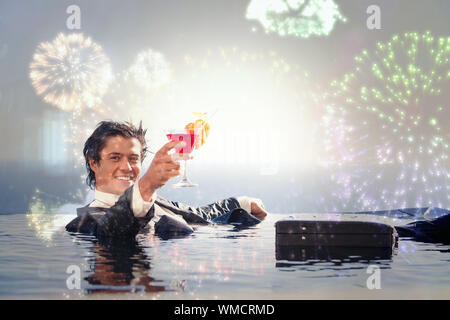Fröhliche Geschäftsmann entspannen in einem Pool mit einem Cocktail gegen buntes Feuerwerk explodierenden auf schwarzem Hintergrund Stockfoto