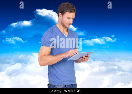 Man Scrollen durch tablet pc vor strahlend blauem Himmel mit Wolken Stockfoto