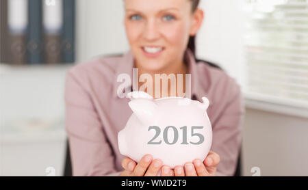 Geschäftsfrau Holding piggy Bank gegen 2015 in Grau Stockfoto