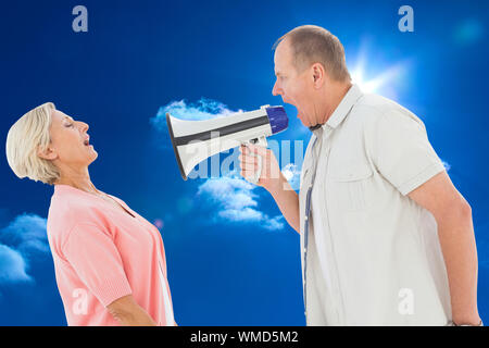 Mann schreit zu seinem Partner durch Megafon gegen strahlend blauen Himmel mit Wolken Stockfoto