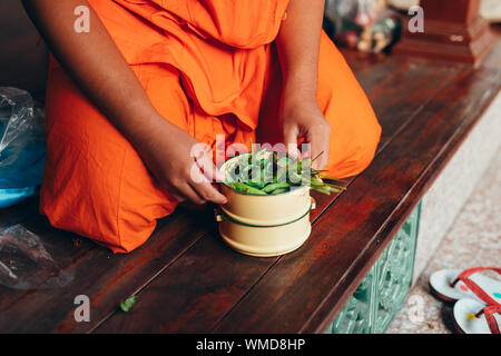 Thailändische Mönch preparring sein Lunchpaket für das Essen von einem Pinto, die voller gesunder Grüns mit Kräutern und Salat traditionelle thailändische Essen gemischt ist Don Stockfoto