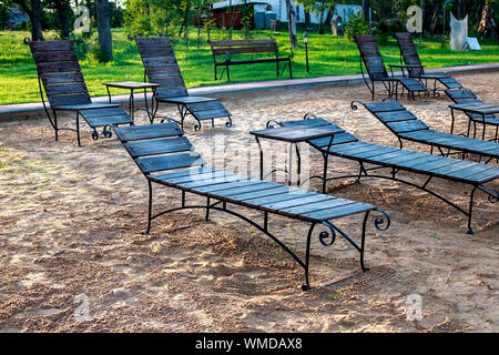 Zone Rest. Holz Sonnenliegen und Stühle mit Tischen stehen am Strand am See, mit Blick auf den See. Weißrussland Stockfoto