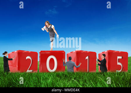 Geschäftsfrau durch Megaphon riefen gegen grüne Feld unter blauem Himmel Stockfoto