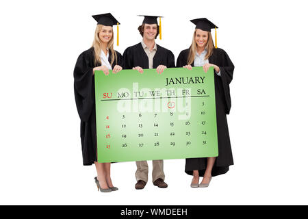 Drei Studenten in der Graduierten robe Holding ein leeres Zeichen gegen die Green Card Stockfoto