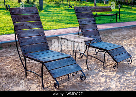 Zone Rest. Holz Sonnenliegen und Stühle mit Tischen stehen am Strand am See, mit Blick auf den See. Weißrussland Stockfoto