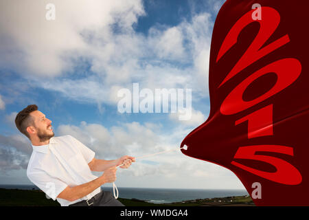 Hipster Geschäftsmann ziehen ein Seil gegen den blauen Himmel mit weißen Wolken Stockfoto