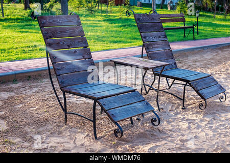 Zone Rest. Holz Sonnenliegen und Stühle mit Tischen stehen am Strand am See, mit Blick auf den See. Weißrussland Stockfoto