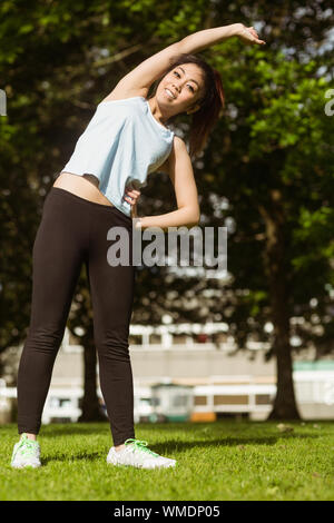 Gesunde und schöne junge Frau zu tun Stretching Übungen im Park Stockfoto