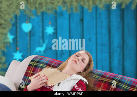 Frau schlafend auf der Couch gegen verwackelte Weihnachtsschmuck über Holz aufhängen Stockfoto