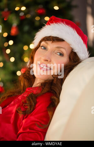 Hübsche Rothaarige in Santa hat an Weihnachten zu Hause im Wohnzimmer Stockfoto