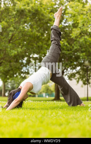 Friedliche braunes Haar Yoga auf Rasen im Park Stockfoto