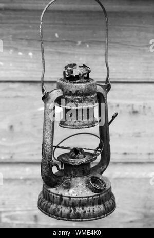 Alte verrostete rot Petroleumlampe auf grau Holz Wand Hintergrund. Schwarz und Weiß, retro style Foto Stockfoto