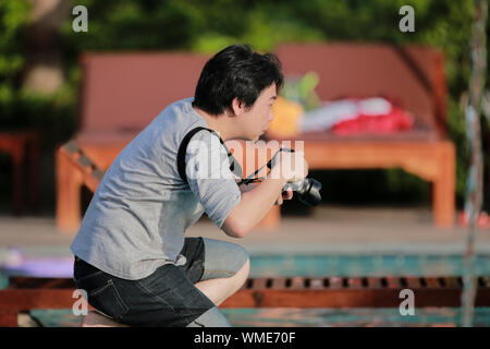 Der Moment der Asiatische Thai professioneller Fotograf ist kniend und warte für ein tolles Foto. Stockfoto
