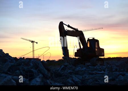 Große Raupenbagger mit hydraulischer Schere auf einer Baustelle vor dem Hintergrund der fantastischen Sonnenuntergang. Road Repair, Asphalt ersetzt werden. S Stockfoto