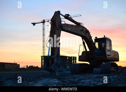 Große Raupenbagger mit hydraulischer Schere auf einer Baustelle vor dem Hintergrund der fantastischen Sonnenuntergang. Road Repair, Asphalt ersetzt werden. S Stockfoto