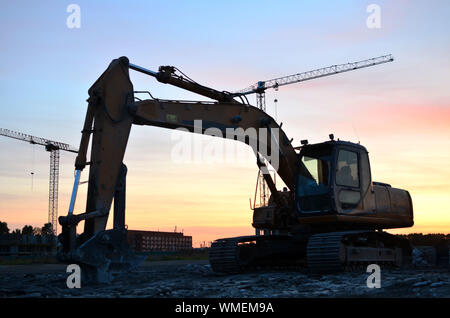 Große Raupenbagger mit hydraulischer Schere auf einer Baustelle vor dem Hintergrund der fantastischen Sonnenuntergang. Road Repair, Asphalt ersetzt werden. S Stockfoto