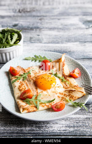 Crepes mit Eiern, Käse, Rucola Blätter und Tomaten. Galette abgeschlossen. Traditionelles Gericht galette Sarrasin Stockfoto