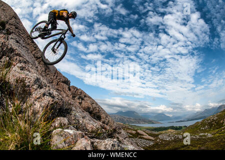 Ein Mann fährt mit einem Mountainbike-Rad eine Felsplatte auf der Halbinsel Applecross im Nordwesten der schottischen Highlands hinunter. Stockfoto