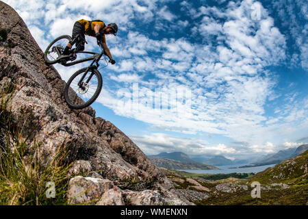 Ein Mann fährt mit einem Mountainbike-Rad eine Felsplatte auf der Halbinsel Applecross im Nordwesten der schottischen Highlands hinunter. Stockfoto