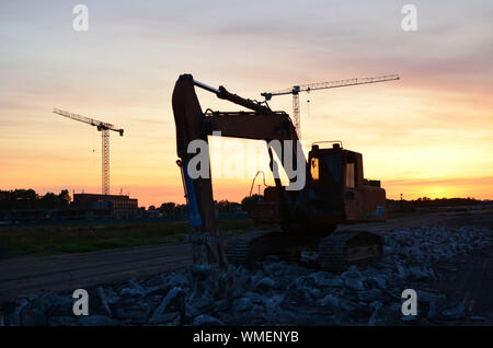 Große Raupenbagger mit hydraulischer Schere auf einer Baustelle vor dem Hintergrund der fantastischen Sonnenuntergang. Road Repair, Asphalt ersetzt werden. S Stockfoto