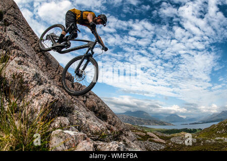 Ein Mann fährt mit einem Mountainbike-Rad eine Felsplatte auf der Halbinsel Applecross im Nordwesten der schottischen Highlands hinunter. Stockfoto